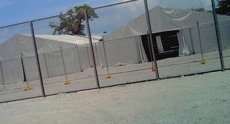 High fences in front of tents in a detention centre