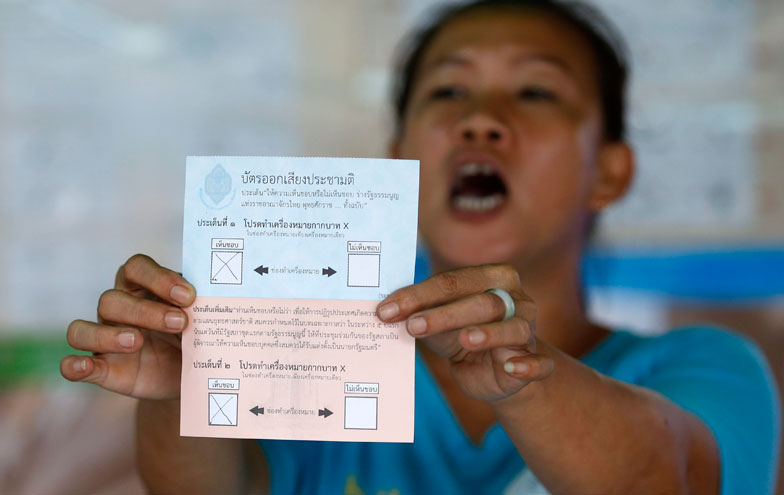 A Thai electoral official displays a ballot paper for the referendum