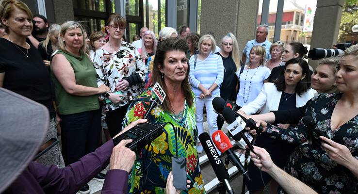 Julie Davis speaking to reporters with microphones