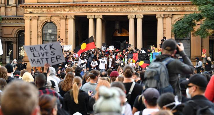 protesters with signs and aboriginal flags outside sydney town hall