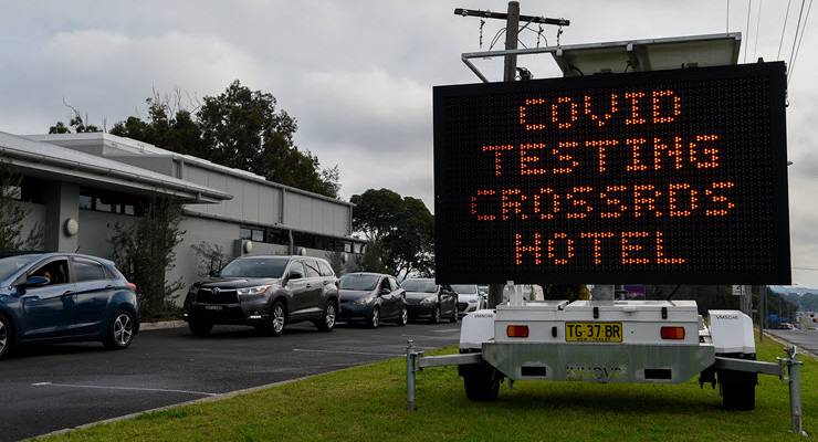 cars queue next for sign reading "covid testing crossroads hotel"
