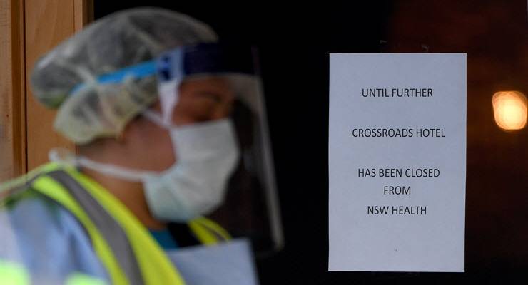 health worker wearing PPE walks past closed signed