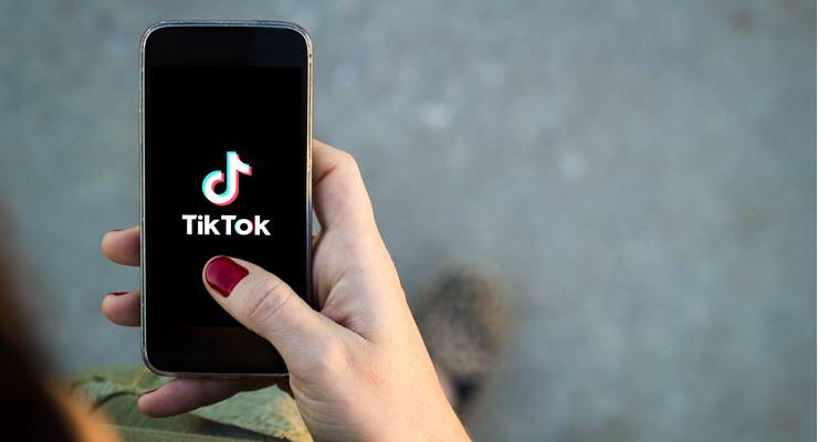 woman holding phone with tiktok logo on screen