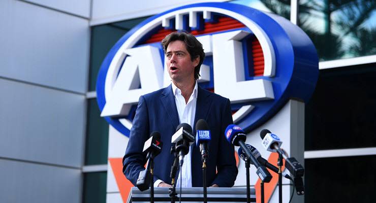 AFL CEO Gillon McLachlan standing in front of the AFL logo and behind microphones a