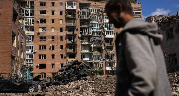 A man walks next to heavily damaged buildings and destroyed cars following Russian attacks in Bakhmut, Donetsk region, eastern Ukraine, Tuesday, May 24, 2022. (AP Photo/Francisco Seco)