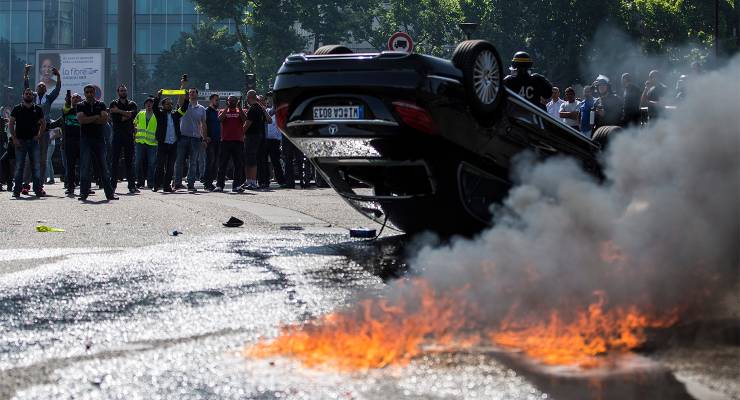 An Uber vehicle overturned by French taxi drivers as they clash with riot police, France, 2015 (Image: AAP/EPA/Ian Langsdon)