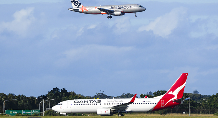 A Jetstar plane prepares to land as a Qantas jet taxis at Sydney Airport