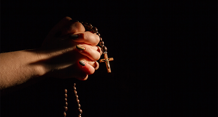 Hands praying with rosary and wooden cross (Image: Adobe)
