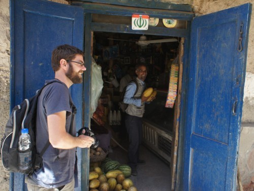 The tourist author of this camera-wielding-tourist-bashing blog post hypocritically wielding a camera. In the background, Vali wields melons as Ayatollahs Khomeini and Khamenei keep stern watch from atop the door.