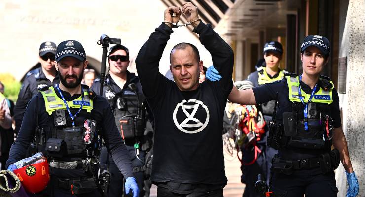 Victoria Police officers detain an activist from Extinction Rebellio (Image: AAP/Joel Carrett)