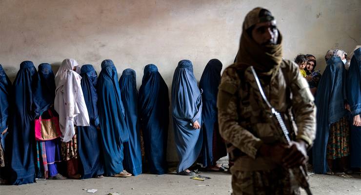 A Taliban fighter stands guard as women wait to receive food rations in Kabul, Afghanistan, May 23, 2023 (Image: AAP/AP/Ebrahim Noroozi)