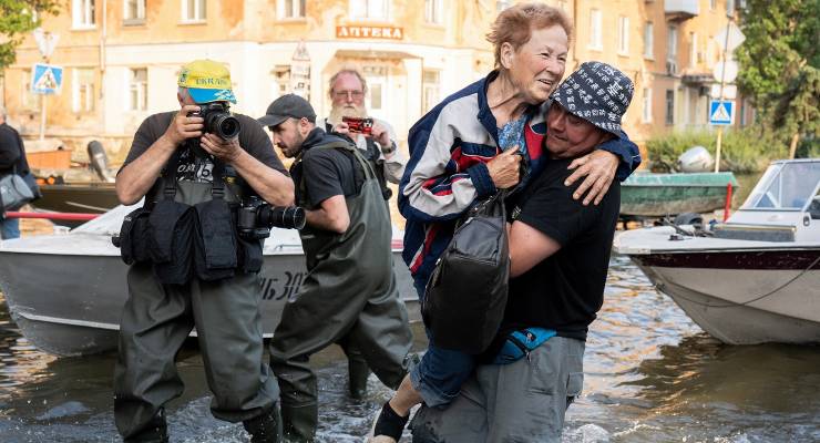A Ukrainian volunteer carries a woman evacuating the flooded city of Kherson