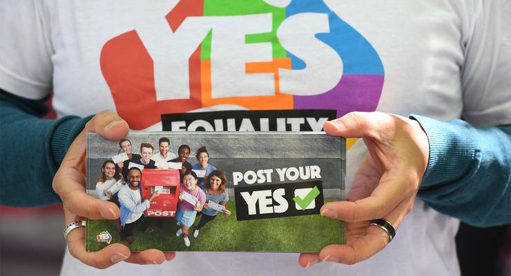 A person handing out Yes vote cards for the marriage equality postal vote in Sydney, 2017 (Image: AAP/Petter Rae)