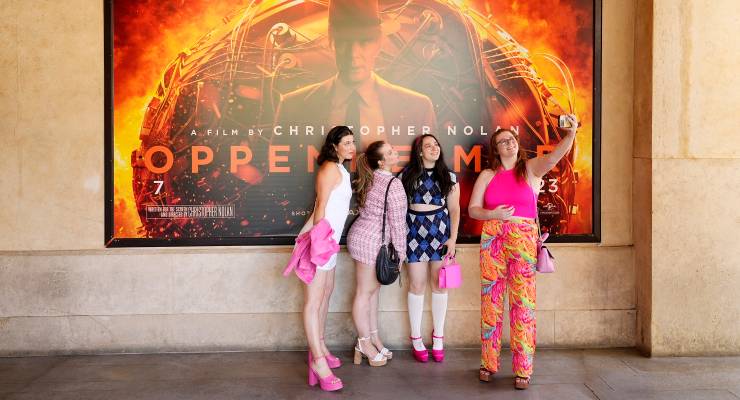Cinemagoers take a photo in front of a poster for Oppenheimer