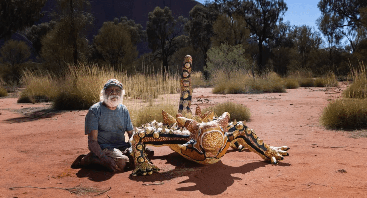Mutitjulu artist Rolley Mintuma seated next to the Ngiyari (thorny devil) sculpture (Image: Supplied/Nancy Green)