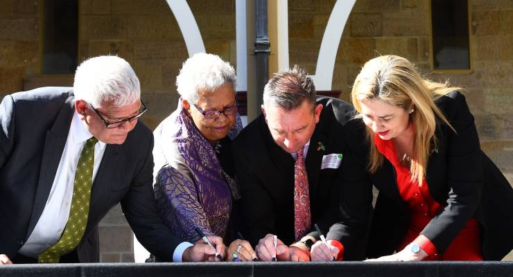 Mick Goodna, Dr Jackie Huggins, Craig Crawford MP and Queensland Premier Annastacia Palaszczuk sign Treaty documents in 2022 (Image: AAP/Jono Searle)