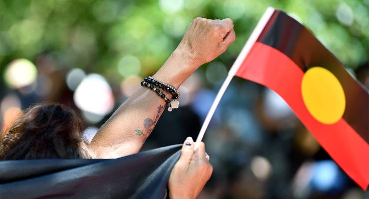 Protestors raise a fist during an Invasion Day rally in Sydney (Image: AAP/Bianca De Marchi)