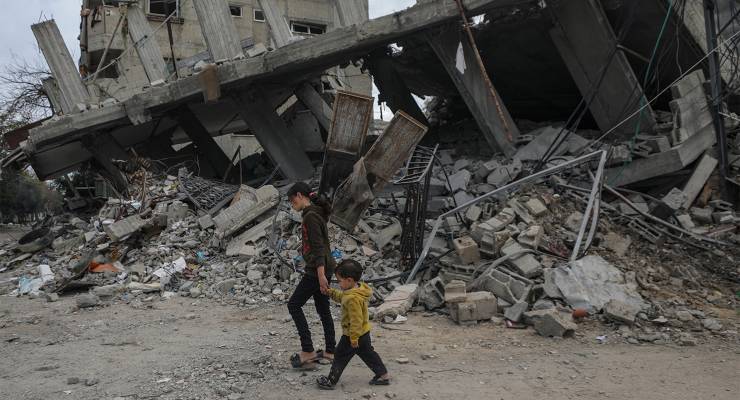 Two Palestinian children walk past destroyed houses during an Israeli military operation in Al Bureije refugee camp, southern Gaza Strip, 13 February (Image: AAP/EPA/Mohammed Saber)